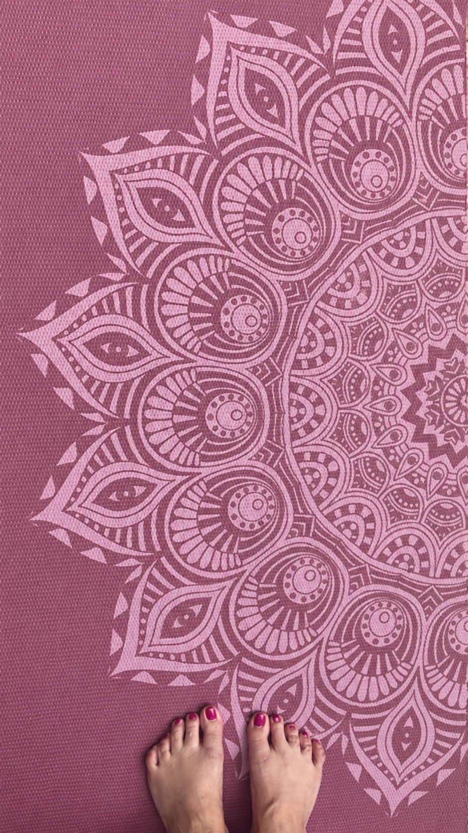 women's feet on a mauve yoga mat with a design